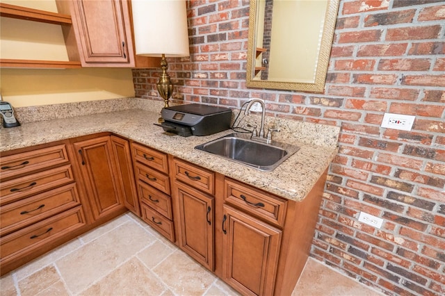 1550 Kevin Ln, Deland, FL 32724 - kitchen featuring a sink, open shelves, light stone counters, brown cabinets, and brick wall