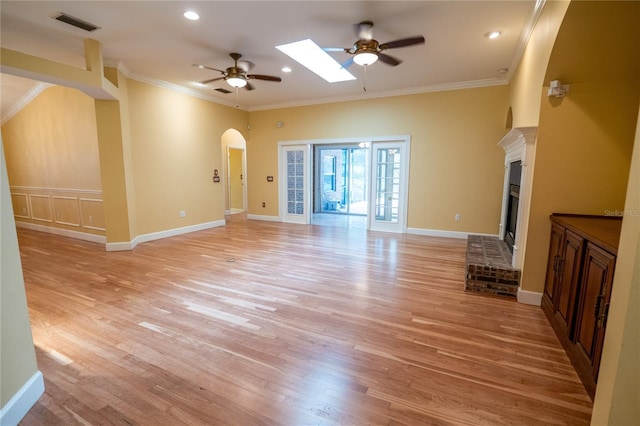 1550 Kevin Ln, Deland, FL 32724 - unfurnished living room featuring a ceiling fan, a brick fireplace, light wood finished floors, ornamental molding, and arched walkways