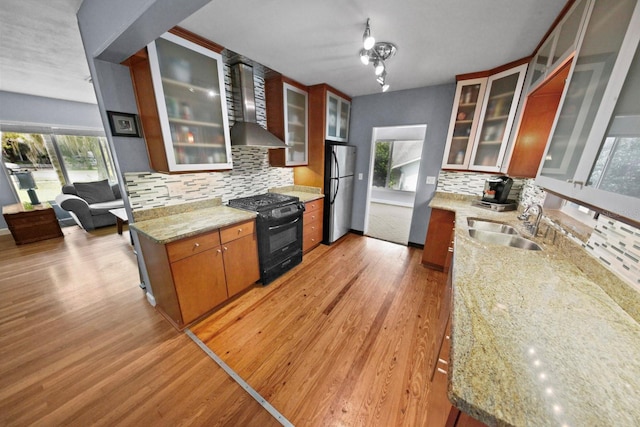 328 E Minnehaha Ave, Clermont, FL 34711 - kitchen featuring gas stove, wall chimney range hood, freestanding refrigerator, light wood-style floors, and a sink