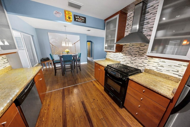 328 E Minnehaha Ave, Clermont, FL 34711 - kitchen featuring black range with gas cooktop, wall chimney range hood, stainless steel dishwasher, dark wood finished floors, and brown cabinetry