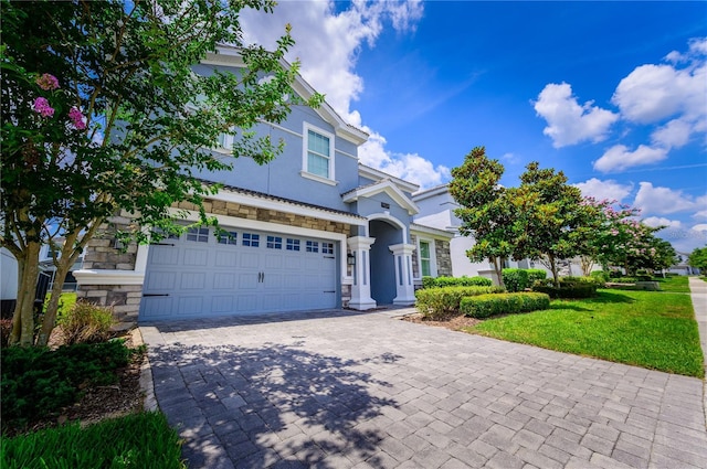 9014 Stinger Dr, Davenport, FL 33896 - view of front of house featuring stone siding, decorative driveway, stucco siding, a garage, and a front lawn