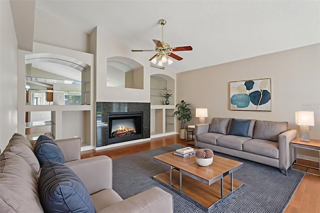970 Sabal Grove Dr, Rockledge, FL 32955 - living room featuring wood finished floors, a glass covered fireplace, ceiling fan, built in shelves, and lofted ceiling
