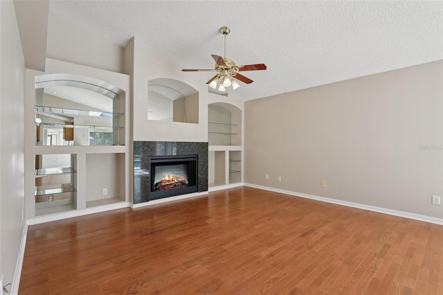 970 Sabal Grove Dr, Rockledge, FL 32955 - unfurnished living room with ceiling fan, wood finished floors, a textured ceiling, a glass covered fireplace, and built in features