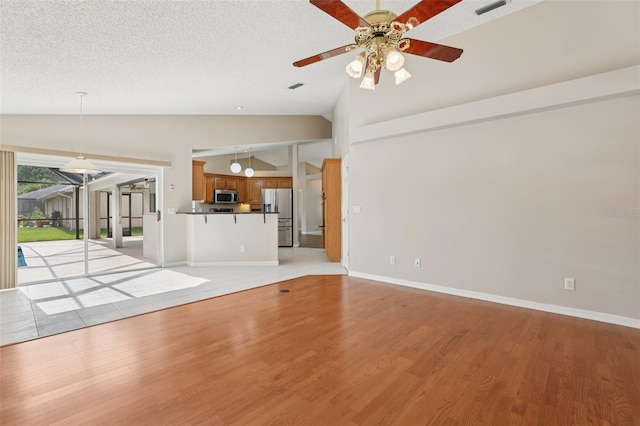 970 Sabal Grove Dr, Rockledge, FL 32955 - unfurnished living room featuring vaulted ceiling, ceiling fan, light wood-type flooring, baseboards, and a textured ceiling