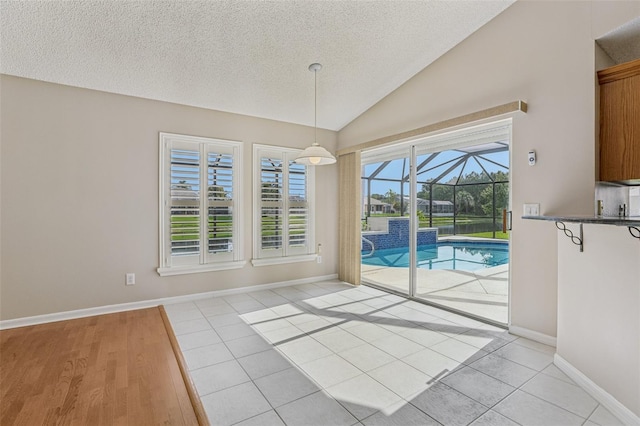 970 Sabal Grove Dr, Rockledge, FL 32955 - unfurnished dining area featuring a sunroom, vaulted ceiling, a textured ceiling, light tile patterned floors, and baseboards