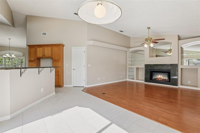 970 Sabal Grove Dr, Rockledge, FL 32955 - unfurnished living room with a ceiling fan, a premium fireplace, a chandelier, light tile patterned flooring, and high vaulted ceiling