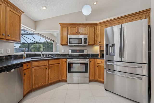 970 Sabal Grove Dr, Rockledge, FL 32955 - kitchen featuring appliances with stainless steel finishes, brown cabinetry, a sink, a textured ceiling, and vaulted ceiling