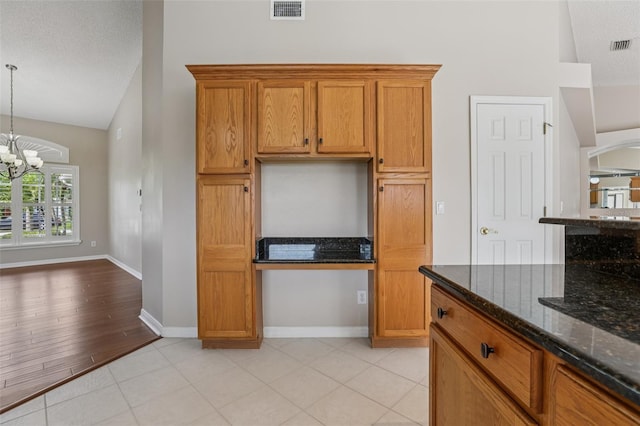 970 Sabal Grove Dr, Rockledge, FL 32955 - kitchen with vaulted ceiling, a chandelier, brown cabinets, dark stone countertops, and a textured ceiling