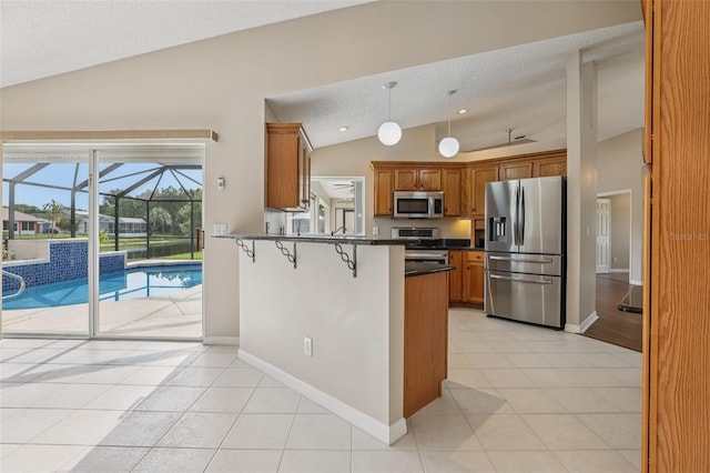 970 Sabal Grove Dr, Rockledge, FL 32955 - kitchen with appliances with stainless steel finishes, lofted ceiling, dark countertops, brown cabinetry, and a peninsula