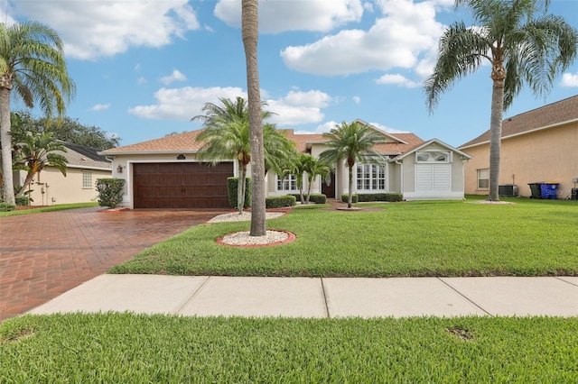 970 Sabal Grove Dr, Rockledge, FL 32955 - view of front of house featuring a garage, decorative driveway, cooling unit, stucco siding, and a front lawn