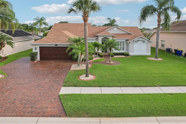 970 Sabal Grove Dr, Rockledge, FL 32955 - mediterranean / spanish house featuring an attached garage, decorative driveway, central AC, and a front lawn