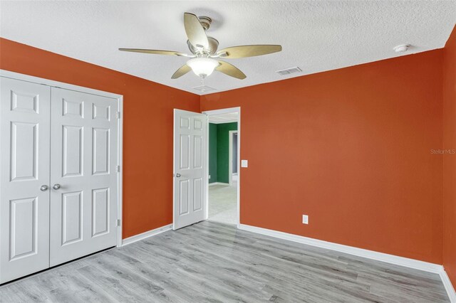 144 Williamson Dr, Davenport, FL 33897 - unfurnished bedroom featuring light wood-style flooring, a closet, baseboards, ceiling fan, and a textured ceiling