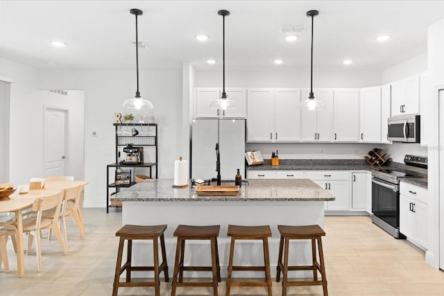 652 SW Mccoy Ave, Port St Lucie, FL 34953 - kitchen with stainless steel appliances, recessed lighting, an island with sink, white cabinetry, and pendant lighting