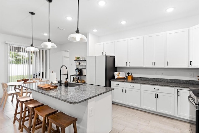 652 SW Mccoy Ave, Port St Lucie, FL 34953 - kitchen with a sink, freestanding refrigerator, white cabinetry, dark stone countertops, and recessed lighting