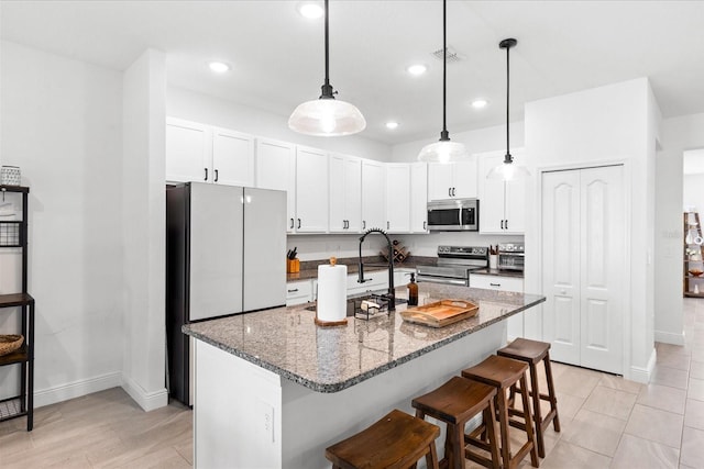 652 SW Mccoy Ave, Port St Lucie, FL 34953 - kitchen featuring appliances with stainless steel finishes, baseboards, recessed lighting, a breakfast bar area, and white cabinets
