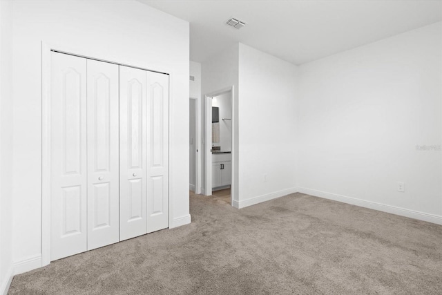652 SW Mccoy Ave, Port St Lucie, FL 34953 - unfurnished bedroom with carpet flooring, a closet, baseboards, and ensuite bathroom
