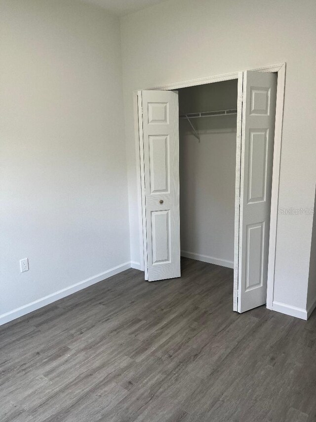 611 Amazon Pl, Kissimmee, FL 34759 - unfurnished bedroom featuring dark wood-style flooring, baseboards, and a closet