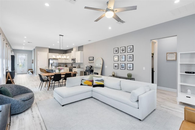 13334 Beebe Aly, Orlando, FL 32827 - living area featuring light wood finished floors, recessed lighting, a chandelier, a ceiling fan, and baseboards