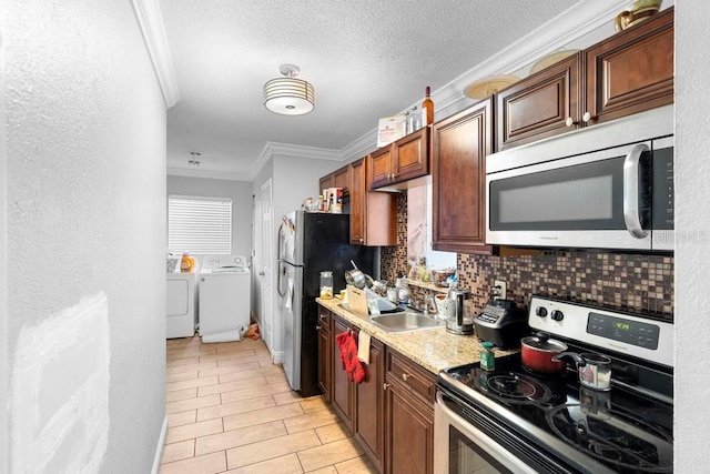 1877 Attucks Ave, Orlando, FL 32811 - kitchen featuring appliances with stainless steel finishes, washing machine and clothes dryer, a sink, ornamental molding, and decorative backsplash
