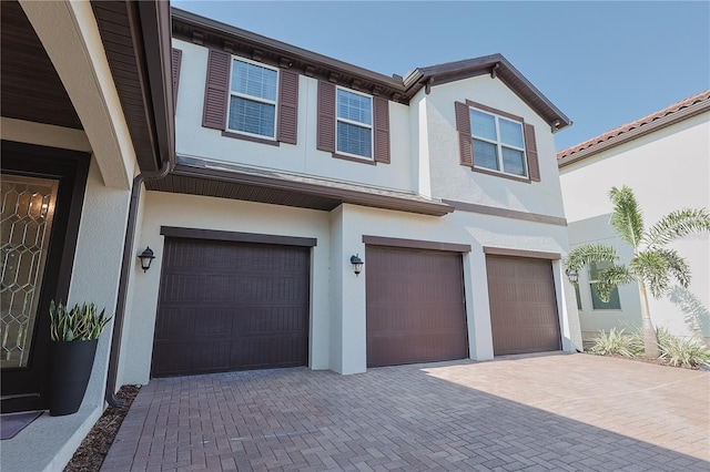 9257 Outlook Rock Trl, Windermere, FL 34786 - view of front of home with an attached garage, stucco siding, and decorative driveway