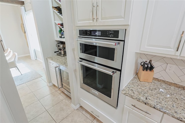 9257 Outlook Rock Trl, Windermere, FL 34786 - kitchen with double oven, backsplash, white cabinetry, wine cooler, and light stone countertops