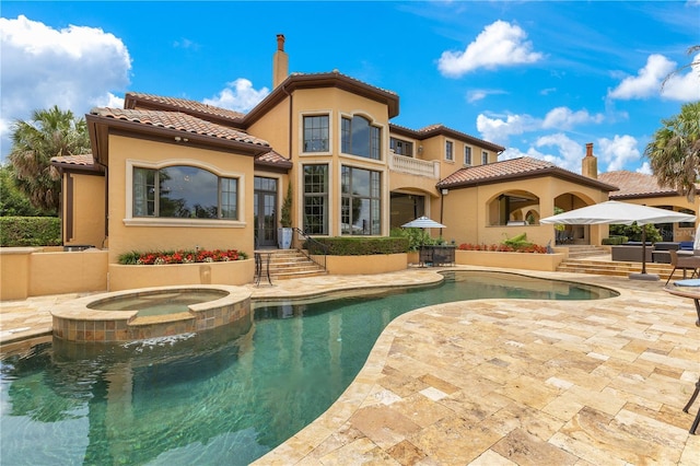 11103 Bridge House Rd, Windermere, FL 34786 - rear view of house featuring a tile roof, a chimney, a patio area, stucco siding, and a pool with connected hot tub