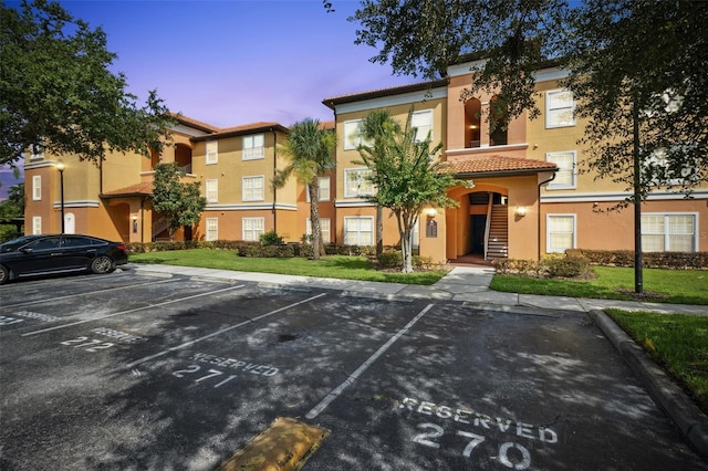 5467 Vineland Rd Unit 6110, Orlando, FL 32811 - view of front of home with uncovered parking, a tiled roof, stucco siding, and a yard