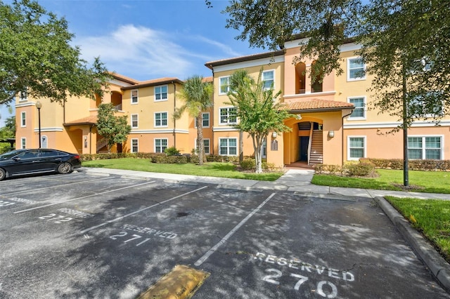 5467 Vineland Rd Unit 6110, Orlando, FL 32811 - view of front of property featuring uncovered parking, stucco siding, a tile roof, and a front lawn