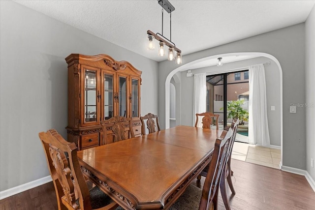 2753 Glenridge Cir, Merritt Island, FL 32953 - dining room featuring arched walkways, dark wood finished floors, baseboards, and a textured ceiling