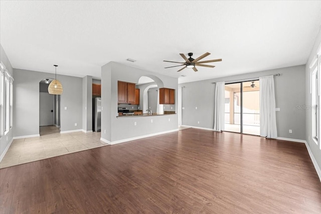 2753 Glenridge Cir, Merritt Island, FL 32953 - unfurnished living room with a ceiling fan, arched walkways, light wood-style flooring, a sink, and baseboards