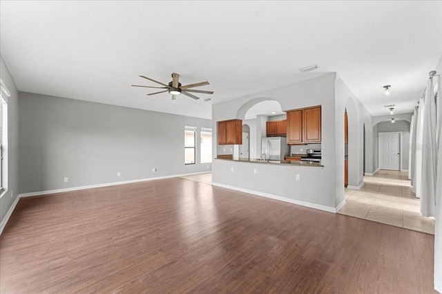 2753 Glenridge Cir, Merritt Island, FL 32953 - unfurnished living room with arched walkways, a ceiling fan, light wood-style floors, and baseboards