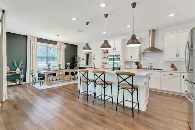 2335 Green Symphony Pl, Oviedo, FL 32765 - kitchen with wall chimney exhaust hood, stainless steel refrigerator, light countertops, backsplash, and a kitchen bar