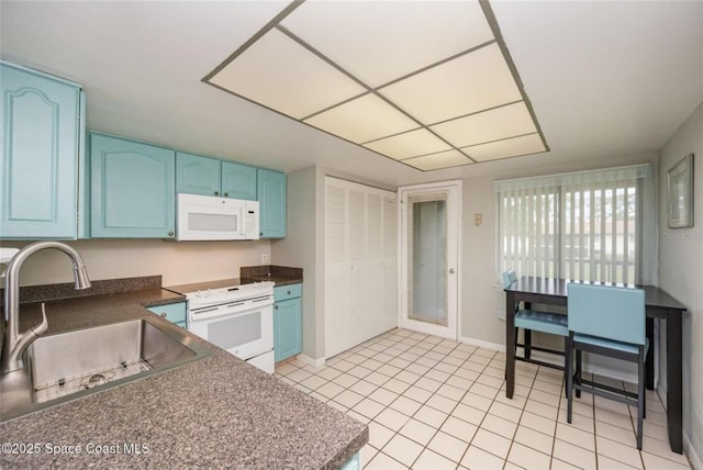 1515 Huntington Ln Unit 426, Rockledge, FL 32955 - kitchen with white appliances, blue cabinets, a sink, dark countertops, and light tile patterned floors