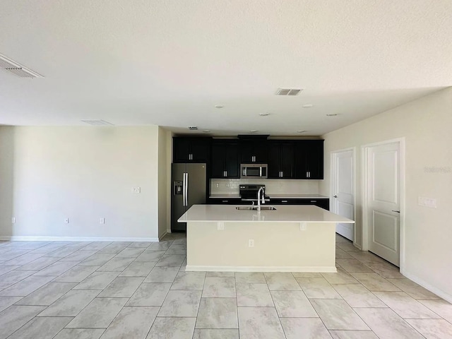 2807 Alder Berry Blvd, Ocoee, FL 34761 - kitchen with stainless steel appliances, dark cabinetry, a sink, an island with sink, and light countertops