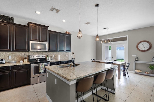 750 Maple Leaf Loop, Winter Springs, FL 32708 - kitchen featuring appliances with stainless steel finishes, a sink, decorative backsplash, light tile patterned floors, and a kitchen island with sink