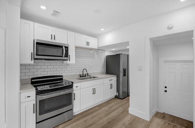 906 Kensington Dr, Orlando, FL 32808 - kitchen with appliances with stainless steel finishes, a sink, light countertops, decorative backsplash, and light wood-style flooring