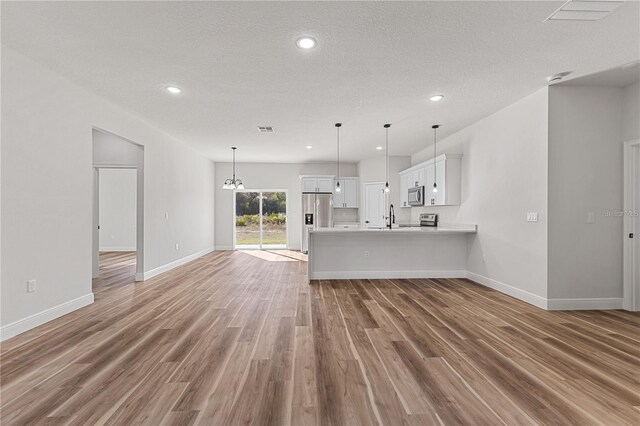 16730 SW 50th Cir, Ocala, FL 34473 - unfurnished living room featuring light wood finished floors, baseboards, recessed lighting, a textured ceiling, and a sink