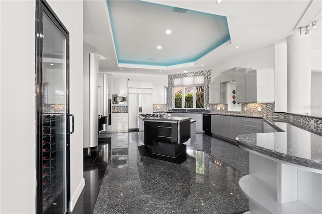 9138 Great Heron Cir, Orlando, FL 32836 - kitchen featuring built in appliances, granite floors, a tray ceiling, decorative backsplash, and dark stone countertops