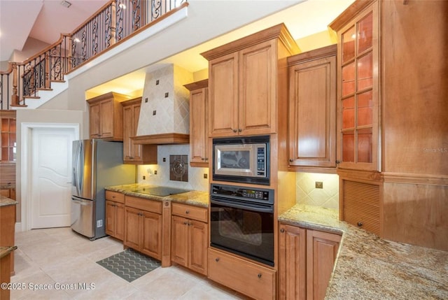 1175 Tuckaway Dr, Rockledge, FL 32955 - kitchen featuring black appliances, premium range hood, light stone counters, glass insert cabinets, and backsplash