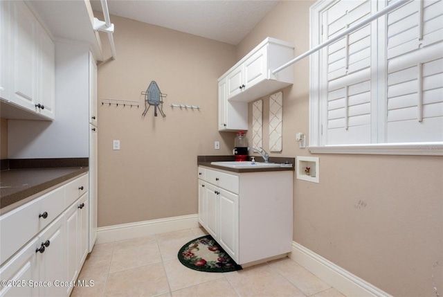 1175 Tuckaway Dr, Rockledge, FL 32955 - kitchen with white cabinets, dark countertops, baseboards, a sink, and light tile patterned flooring