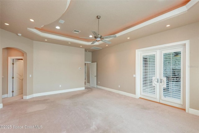 1175 Tuckaway Dr, Rockledge, FL 32955 - unfurnished bedroom with a tray ceiling, light carpet, access to exterior, arched walkways, and baseboards
