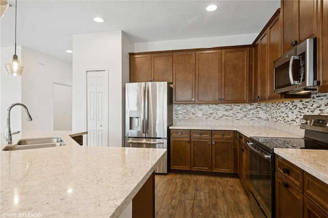 2659 Magpie Way, Sanford, FL 32773 - kitchen featuring appliances with stainless steel finishes, a sink, light stone counters, dark wood finished floors, and hanging light fixtures