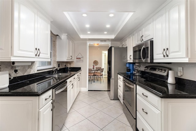 7058 Archwood Dr, Orlando, FL 32819 - kitchen with appliances with stainless steel finishes, a sink, a tray ceiling, backsplash, and white cabinetry