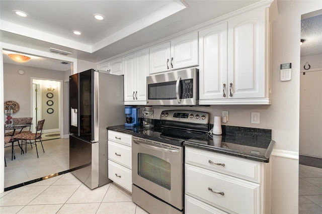 7058 Archwood Dr, Orlando, FL 32819 - kitchen with appliances with stainless steel finishes, light tile patterned floors, white cabinets, dark stone counters, and baseboards