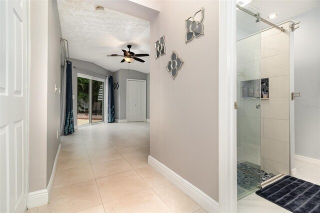 7058 Archwood Dr, Orlando, FL 32819 - hallway with light tile patterned floors, baseboards, vaulted ceiling, and a textured ceiling