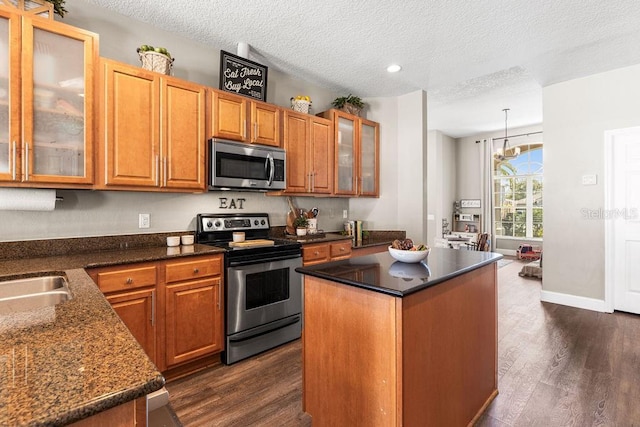 610 Strihal Loop, Oakland, FL 34787 - kitchen featuring stainless steel appliances, dark wood-type flooring, a textured ceiling, a kitchen island, and brown cabinetry