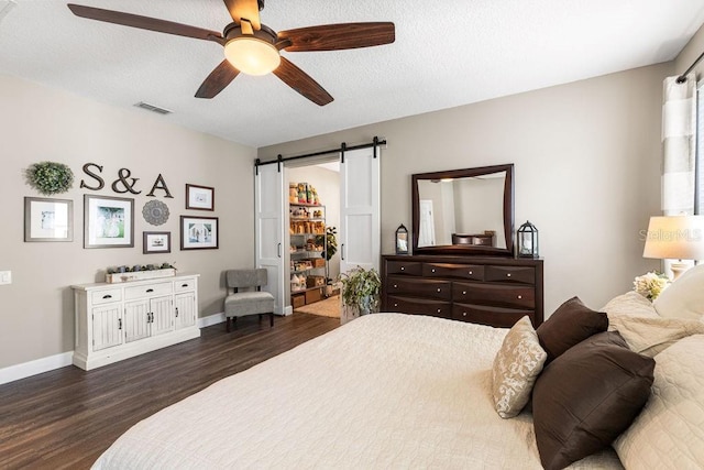 610 Strihal Loop, Oakland, FL 34787 - bedroom featuring dark wood finished floors, a barn door, baseboards, and a ceiling fan