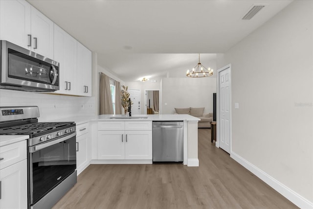 3622 Huntwicke Blvd, Davenport, FL 33837 - kitchen featuring appliances with stainless steel finishes, a sink, a peninsula, light wood-style floors, and a chandelier