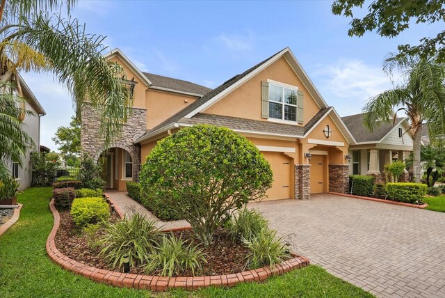 1613 Water Elm Ct, Orlando, FL 32825 - view of front of property featuring stucco siding, stone siding, decorative driveway, a garage, and a front lawn
