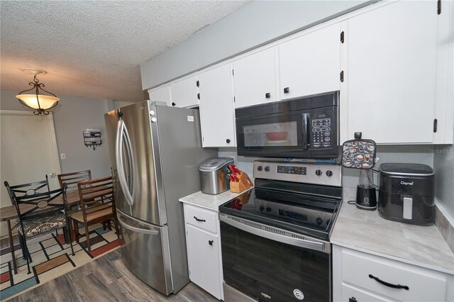 881 Cedar Cir, Tavares, FL 32778 - kitchen with stainless steel appliances, wood finished floors, light countertops, a textured ceiling, and white cabinetry